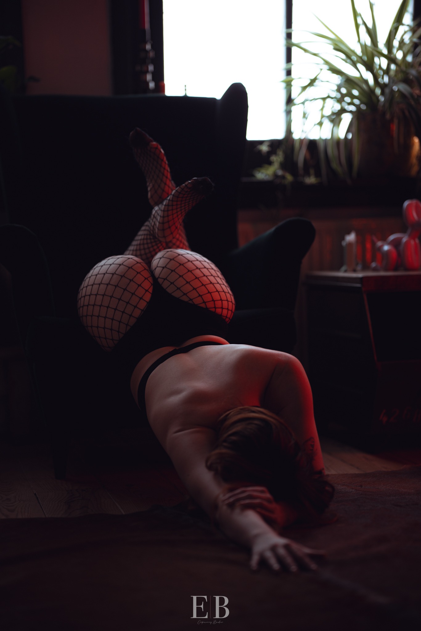 Vrouw in rode lingerie op de vloer, in gedempt rood licht